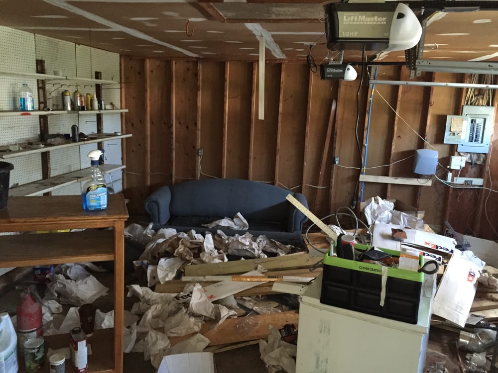 A garage filled with junk and garbage, including an old blue couch