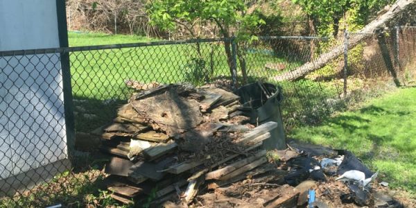 Some wood and construction debris in the corner of a grassy yard